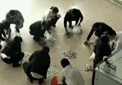 Chinese car dealership staff count one-yuan coins a Chinese man used to pay for his car.