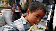  A migrant child eats his lunch at a market in Beijing, China