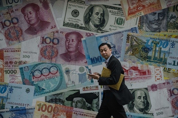 A man walks past a display showing various Chinese bank notes