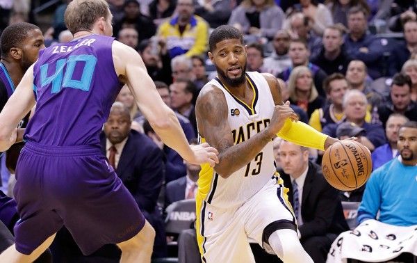 Indiana Pacers forward Paul George (R) drives past two Charlotte Hornets defenders