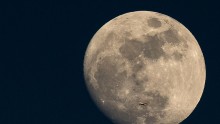 A Plane Is Dwarfed As It Flies Past The Moon