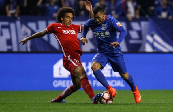 Tianjin Quanjian midfielder Axel Witsel (L) competes for the ball against Shanghai Shenhua's Carlos Tevez