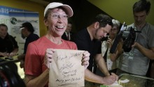  Deb Greene of Seattle, the first customer at Cannabis City, holds up her purchase signed by owner James Lathrop during the first day of legal retail marijuana sales in Seattle, Washington July 8, 2014.