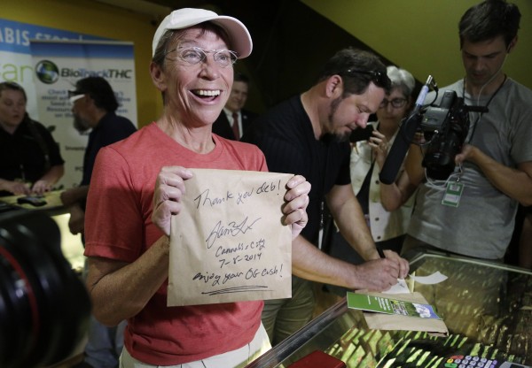  Deb Greene of Seattle, the first customer at Cannabis City, holds up her purchase signed by owner James Lathrop during the first day of legal retail marijuana sales in Seattle, Washington July 8, 2014.