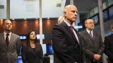 California Governor Jerry Brown (front) waits to speak at a news conference at the Cal OES State Operations Center in Mather, California, February 19, 2014.