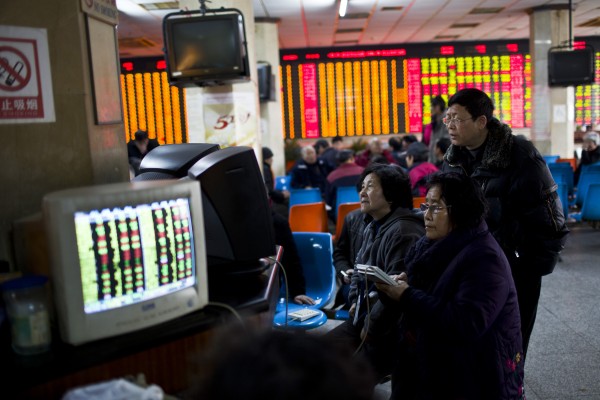 Investors look at computer screens showing stock information at a brokerage house in Shanghai.