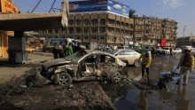 People clean up in the aftermath of a car bomb attack in Baghdad, January 15, 2014.