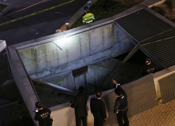 Local authorities stand before the collapsed ventilation shaft in Seongnam, Seoul, October 17, 2014.