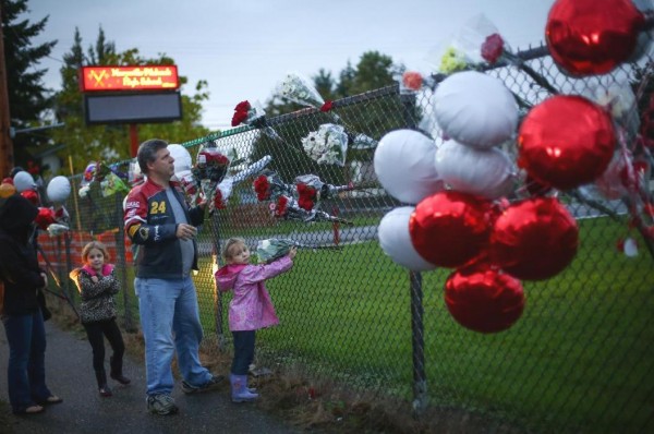 Rick Hartwig places flowers with his daughters Cailin, 6, and Chloe, 5, right, as the memorial grows Saturday Oct. 25, 2014