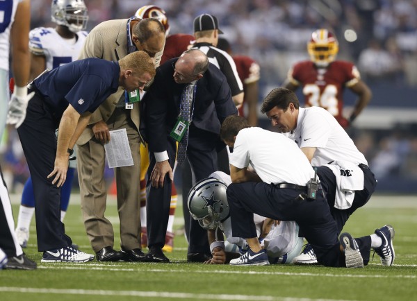 ct 27, 2014; Arlington, TX, USA; Dallas Cowboys quarterback Tony Romo (9) lays on the field injured as trainers, doctors and head coach Jason Garrett check on him in the this quarter against the Washington Redskins at AT&T Stadium. 