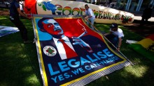Members of the Help End Marijuana Prohibition (HEMP) Party lift a banner displaying a parody of U.S. President Barack Obama's election campaign poster.
