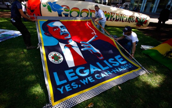 Members of the Help End Marijuana Prohibition (HEMP) Party lift a banner displaying a parody of U.S. President Barack Obama's election campaign poster.