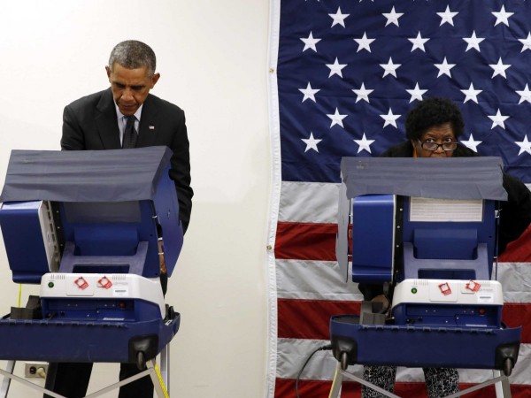 A woman looks up from a voting booth as U.S. President Barack Obama takes part in early voting at a polling station in Chicago, Illinois, October 20, 2014.