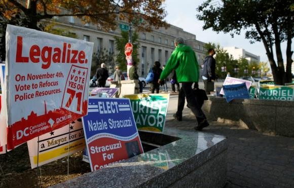 Pedestrians pass by a DC Cannabis Campaign sign in Washington November 4, 2014.