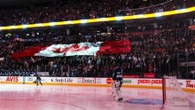 Toronto Maple Leafs goalie James Reimer stands while the Canadian national anthem is played as fans hold a giant Canadian flag before his team plays the Philadelphia Flyers in their NHL hockey game in Toronto, February 11, 2013.