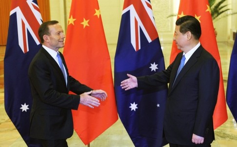 Chinese President Xi Jinping (right) extends his hand to greet Australian Prime Minister Tony Abbott before a meeting at the Great Hall of the People in Beijing on April 11, 2014.