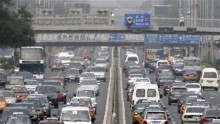 Pedestrians walk across a bridge as cars travel along a main road on a hazy day in central Beijing August 12, 2011.