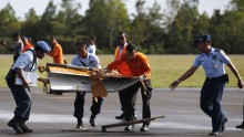 Indonesian Airforce personnel carry suspected debris