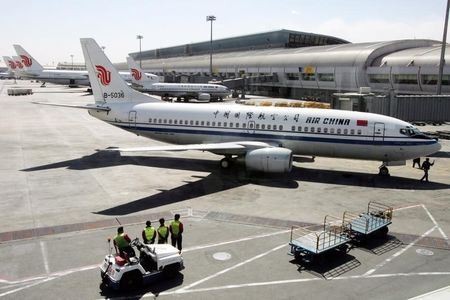 Chinese workers in Beijing airport stand in front of an Air China aircraft. Photo taken on March 25, 2005.