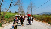 Refugees who have been displaced by recent violence in Myanmar, walk down a road with bundles of belongings. February 17, 2015. 