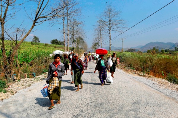 Refugees who have been displaced by recent violence in Myanmar, walk down a road with bundles of belongings. February 17, 2015. 