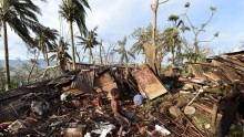 A boy called Samuel kicks a ball as his father Phillip searches through the ruins of their home which was destroyed by Cyclone Pam in Port Vila, Vanuatu March 16, 2015. 