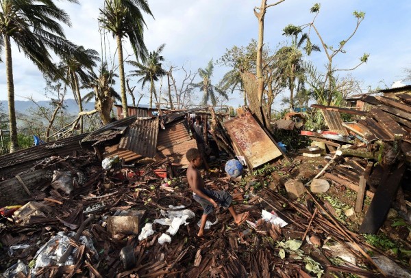 A boy called Samuel kicks a ball as his father Phillip searches through the ruins of their home which was destroyed by Cyclone Pam in Port Vila, Vanuatu March 16, 2015. 