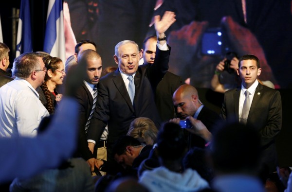 Israeli Prime Minister Benjamin Netanyahu (C) waves to supporters at party headquarters in Tel Aviv March 18, 2015.