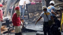 Workers look as police carry a body bag containing the charred remains of a worker inside the gutted slipper factory in Valenzuela, Philippines May 14, 2015
