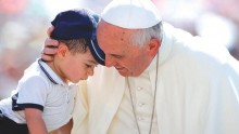 Pope Francis hugging a child at a weekly papal audience in St. Peter's Square, Vatican City.