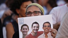 An Israeli woman holding a sign showing images of the three abducted teenagers in Tel Aviv Sunday.