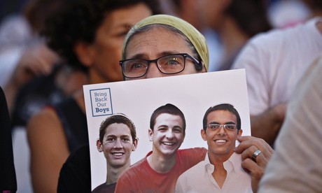 An Israeli woman holding a sign showing images of the three abducted teenagers in Tel Aviv Sunday.