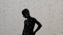A boy cools himself off as he stands under a water fountain in New Delhi on Saturday. 