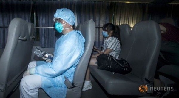 A health worker wears a protective suit while sitting with people who came in close contact with the Korean Mers patient.