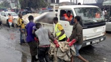 Rescue workers carry a corpse to a truck from the remains of the gas station.