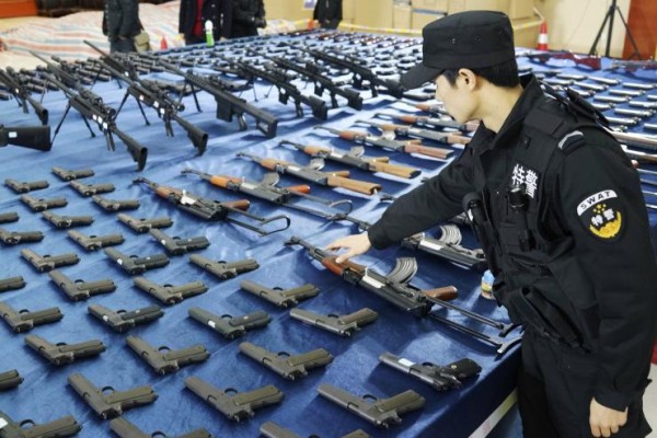 A policeman checks on confiscated illegal replica guns in Guiyang, Guizhou province