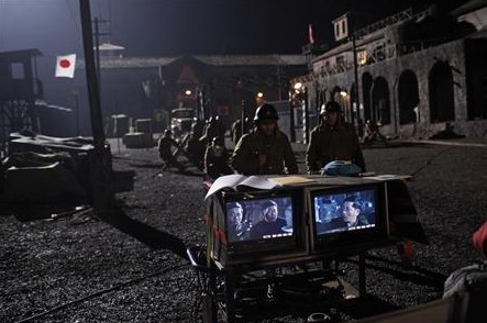 Actors in Japanese military uniforms watch a replay of a scene during the filming of an anti-Japanese World War Two film