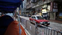 A taxi drives past tents at a protest site after police removed some barricades, at the commercial area of Causeway Bay in Hong Kong October 14, 2014.