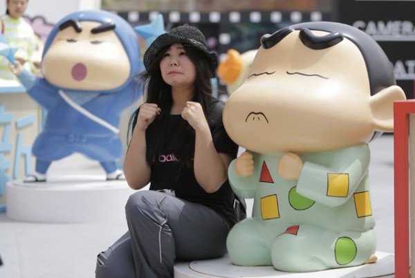 A visitor poses for a photo with a Crayon Shin-chan model during an exhibition at Joy City in Beijing 