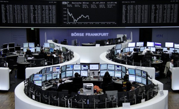 Traders are pictured at their desks in front of the DAX board at the Frankfurt stock exchange July 21, 2014. 