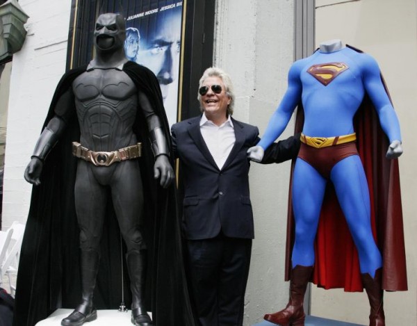 Film producer Jon Peters poses with costumes of Batman (left) and Superman.