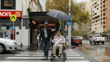 A Woman in Wheelchair Crosses Street