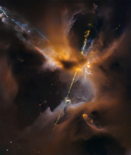 The two lightsaber-like streams crossing the image are jets of energised gas, ejected from the poles of a young star. If the jets collide with the surrounding gas and dust they can clear vast spaces, and create curved shock waves, seen as knotted clumps c