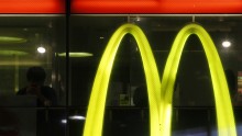 A customer using his mobile phone is seen next to a McDonald's logo at a McDonald's store in Tokyo July 22, 2014.