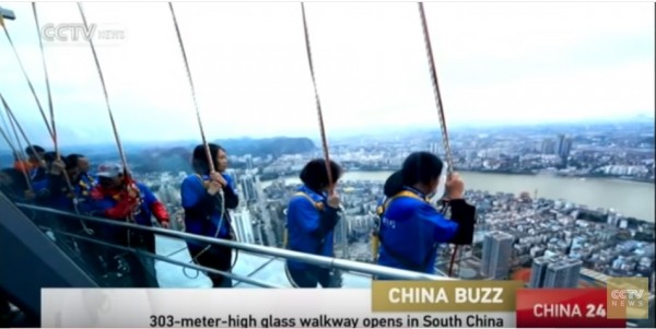 Chinese tourists holding onto their rope and secured with harness take a look at the overlooking city view