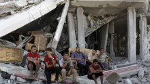 Palestinians sit amid the ruins of destroyed homes in the Shejaia neighbourhood, which witnesses said was heavily hit by Israeli shelling and air strikes during an Israeli offensive, in Gaza City. . 