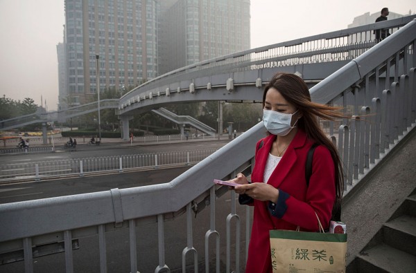 A Chinese woman wears a mask as she crosses a foot-bridge