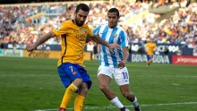Barcelona midfielder Arda Turan (L) competes for the ball against Malaga's Roberto Rosales