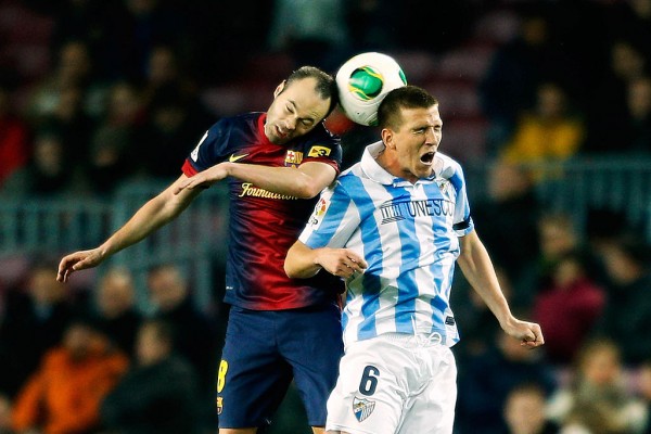 Malaga midfielder Ignacio Camacho (R) competes for the ball against Barcelona's Andres Iniesta