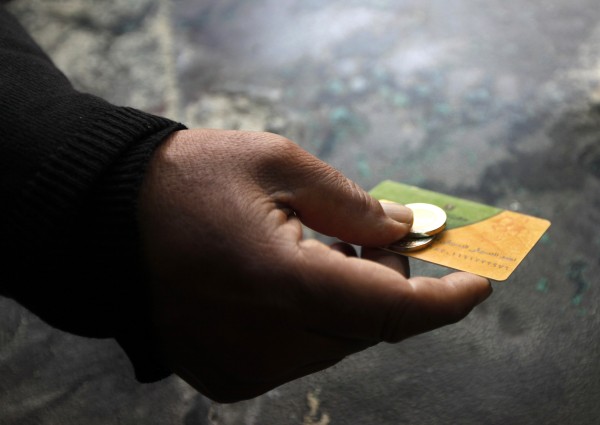 A man holds his smart card and some coins at a bakery in the Suez Canal city of Port Said, 170 km (106 miles) northeast of Cairo, February 24, 2014. A device resembling a credit card swiper is revolutionizing some of Egypt's politically explosive bread li